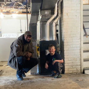 HVAC tech posing with homeowner's son after their household won the Scary Furnace Giveaway Contest.