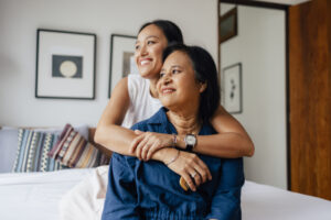 a mother and daughter hugging and looking happy.